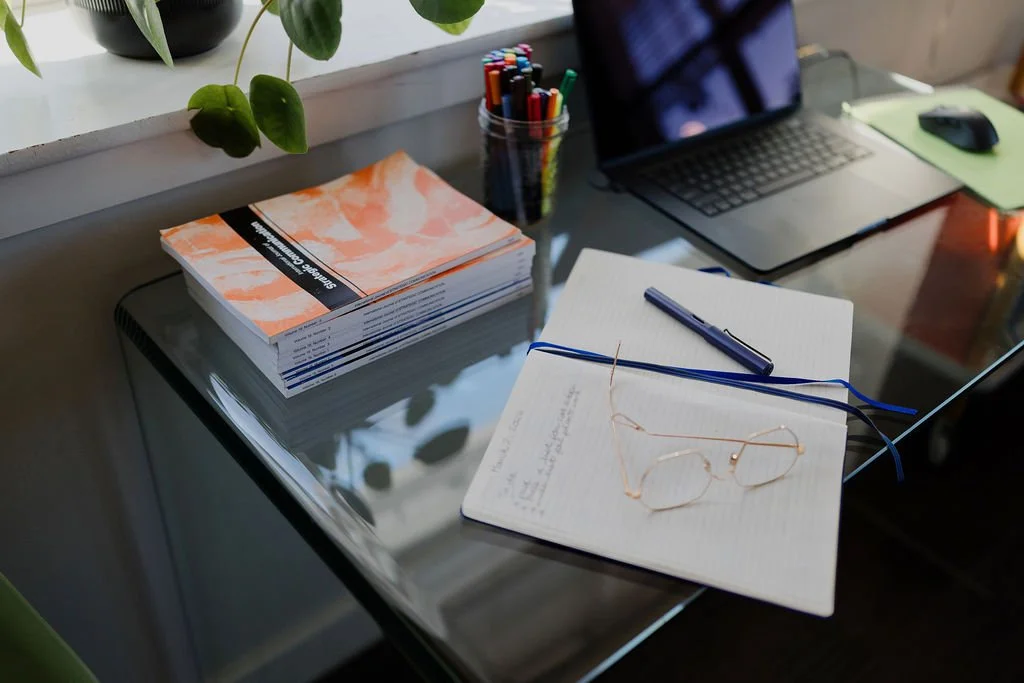 Gather Strategy communications consultant workspace with notebook, laptop and strategic planning materials.
