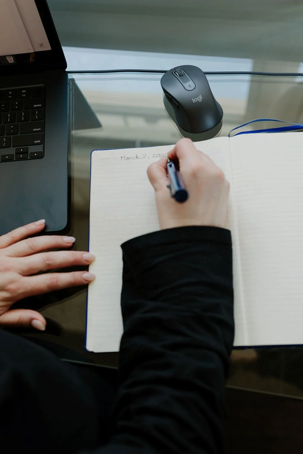Communications consultant taking notes during strategic communications planning at a desk with a laptop and notebook.