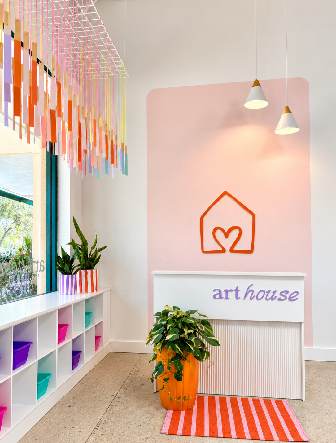 Art House creative art studio interior in Boca Raton with a pink arch, plants, and the Art House logo