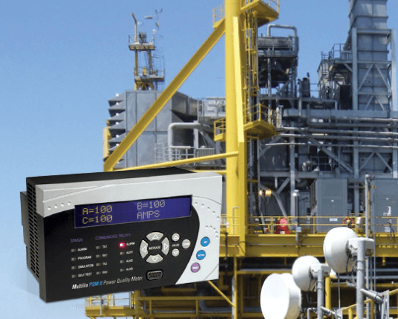 Industrial plant with yellow and gray structures, and an electronic power quality monitor in the foreground.