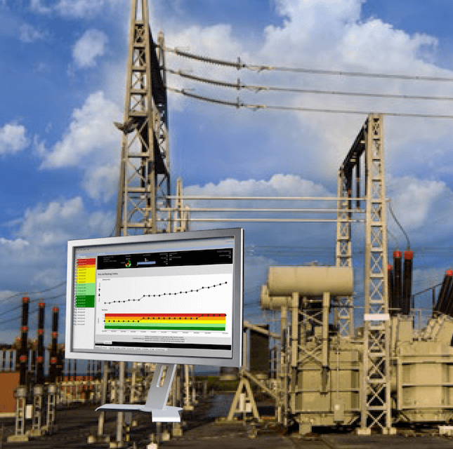 Industrial power substation with electrical transformers and transmission towers, and a computer monitor displaying a graph and data analysis, set against a blue sky with clouds.