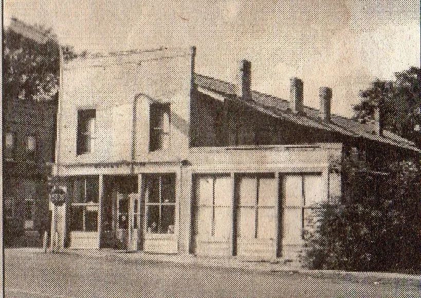 An old black and white photo of a modern-style building with large windows and a curved entrance, with a person standing in front of the building.