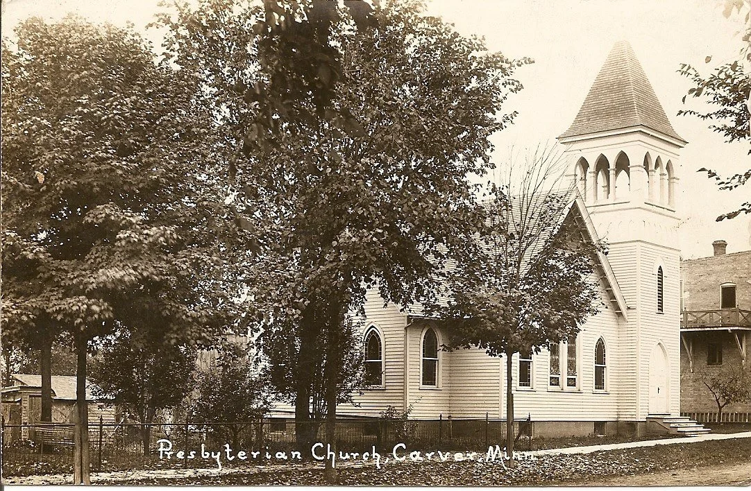 A sepia-toned image of a white wooden Presbyterian church with a steeple, surrounded by trees and a black fence.