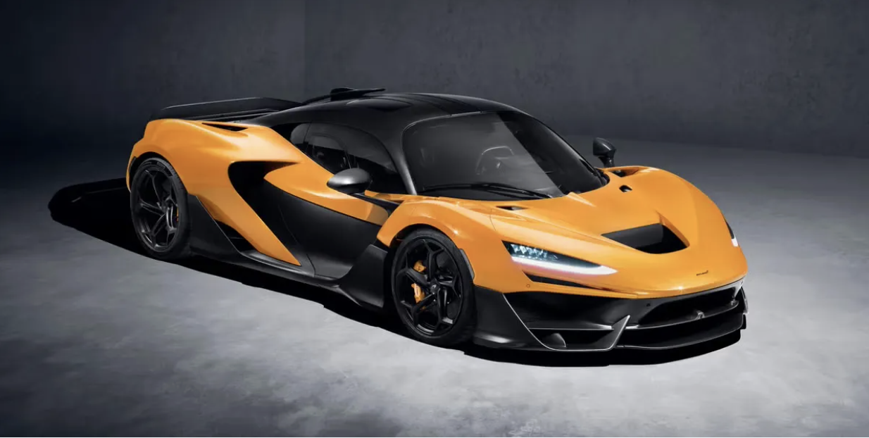 A sleek, modern sports car with an orange and black exterior in a dimly lit setting.
