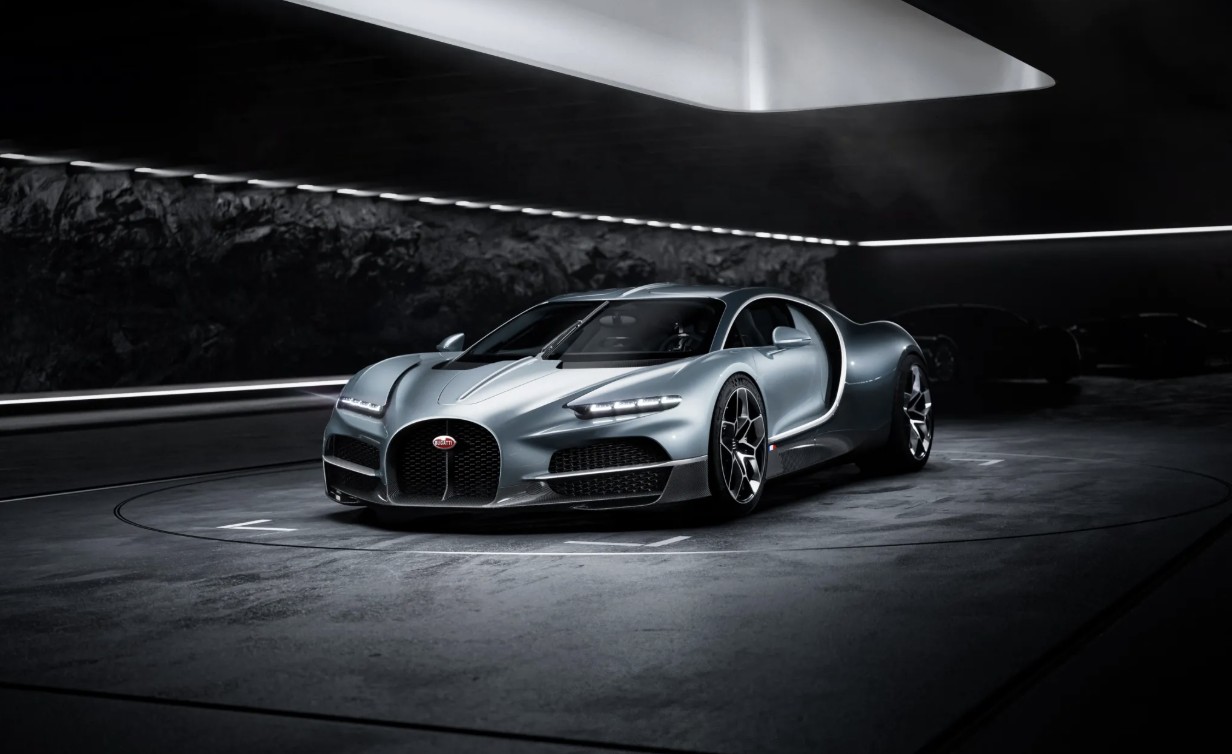 A silver Bugatti Chiron sports car inside a modern, dark garage with minimal lighting.