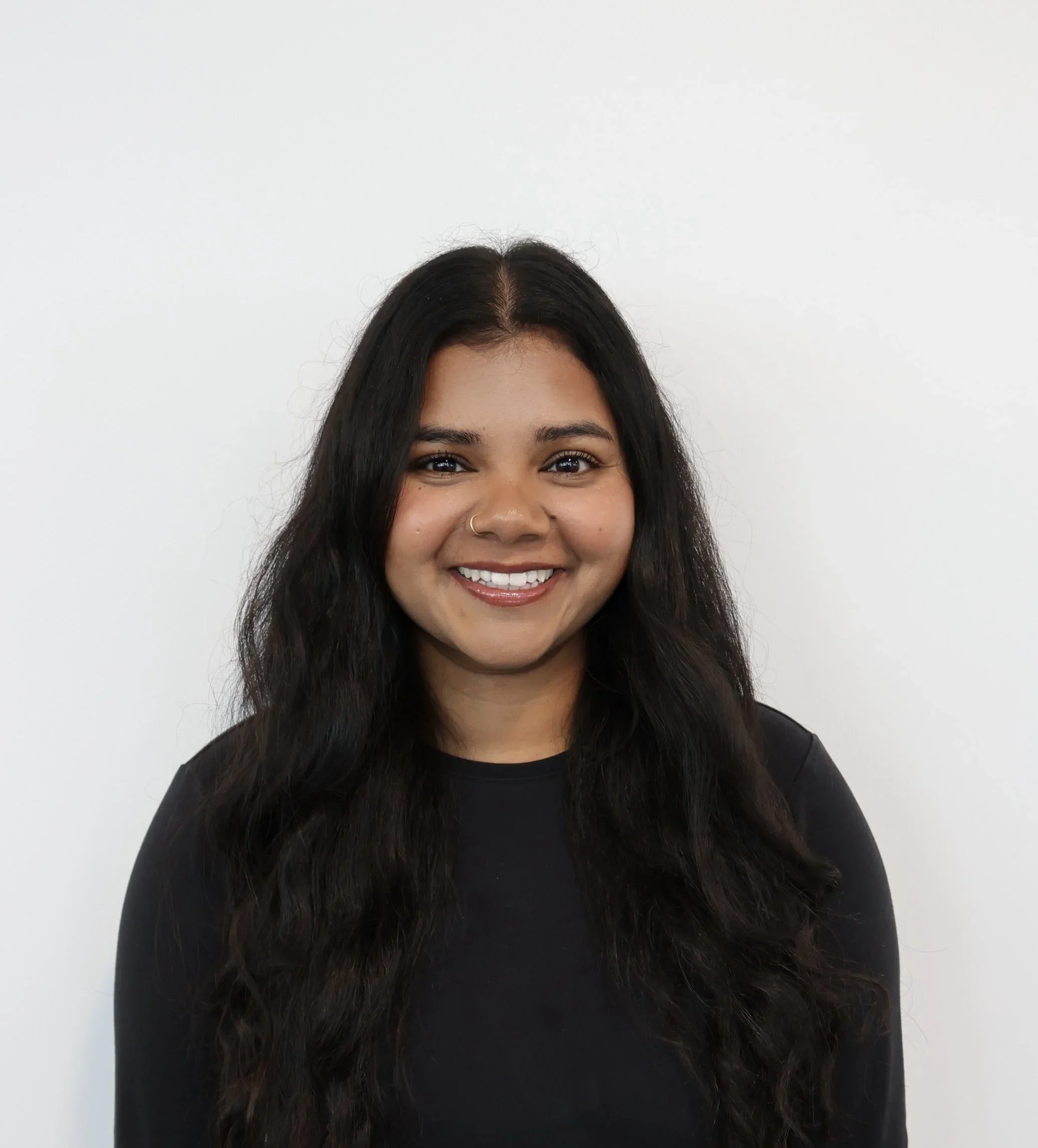 Professional headshot of a smiling woman with long dark hair wearing a black top.