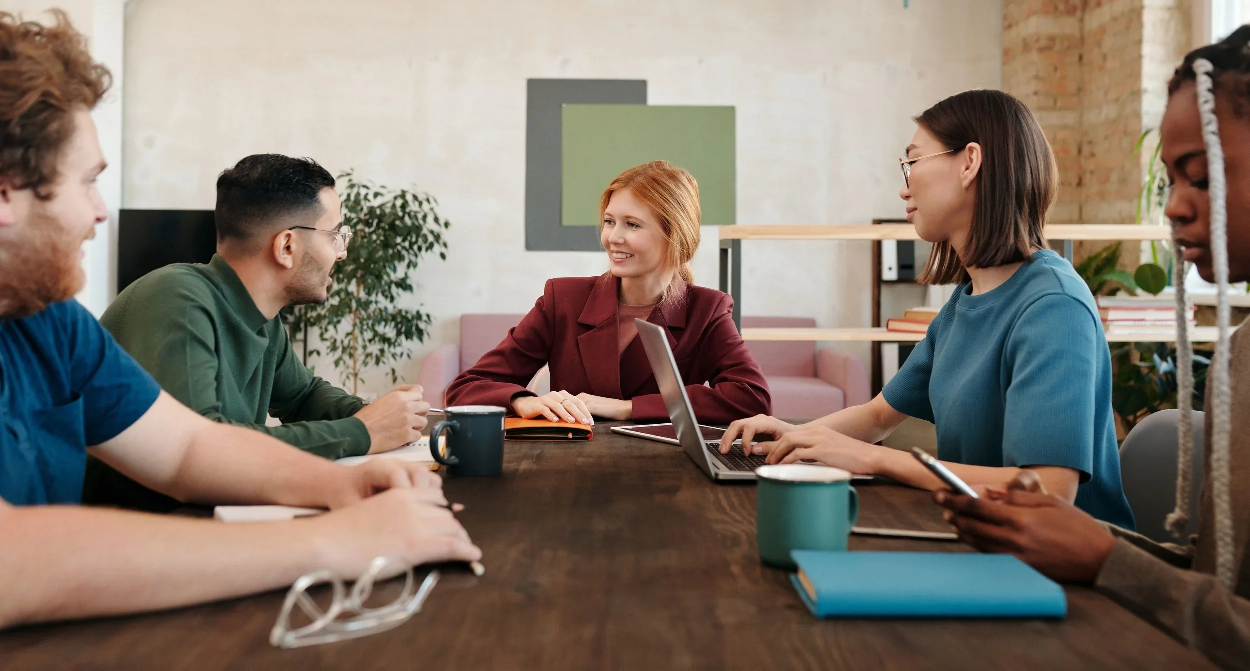 Five people collaborating around a table during a team meeting.
