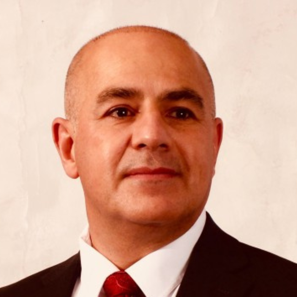 Professional headshot of a man wearing a suit and red tie.