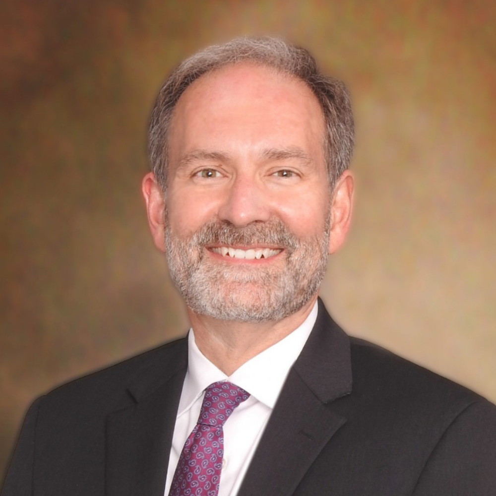 Professional headshot of a smiling man in a suit and tie.