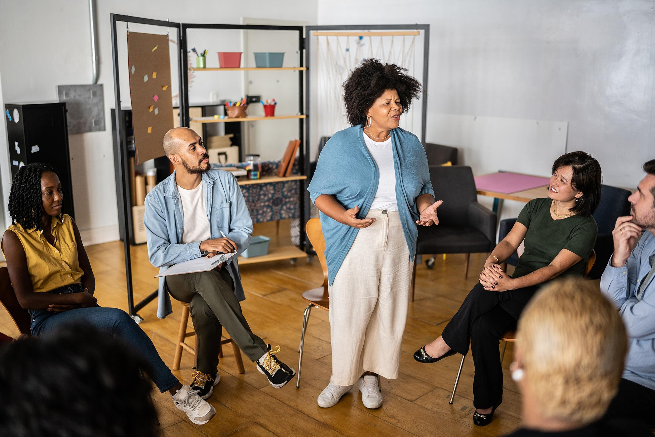 Person speaking to a seated group during a workshop or discussion.