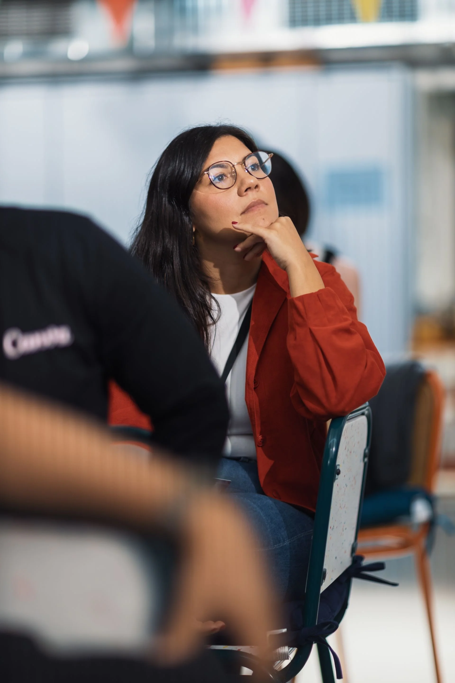Woman with glasses listening attentively during a workshop or presentation.