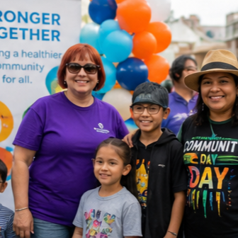 Two adults and two children smiling together at a community event.