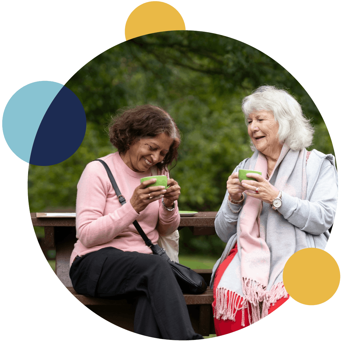 Two women laughing together on a park bench.