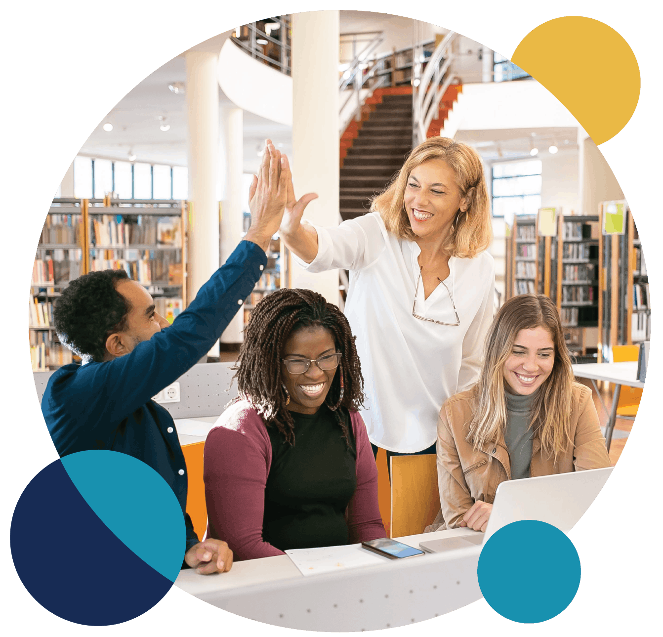 A group of four diverse women, three seated and one standing, in a library or bookstore, smiling and giving high-fives amidst bookshelves.