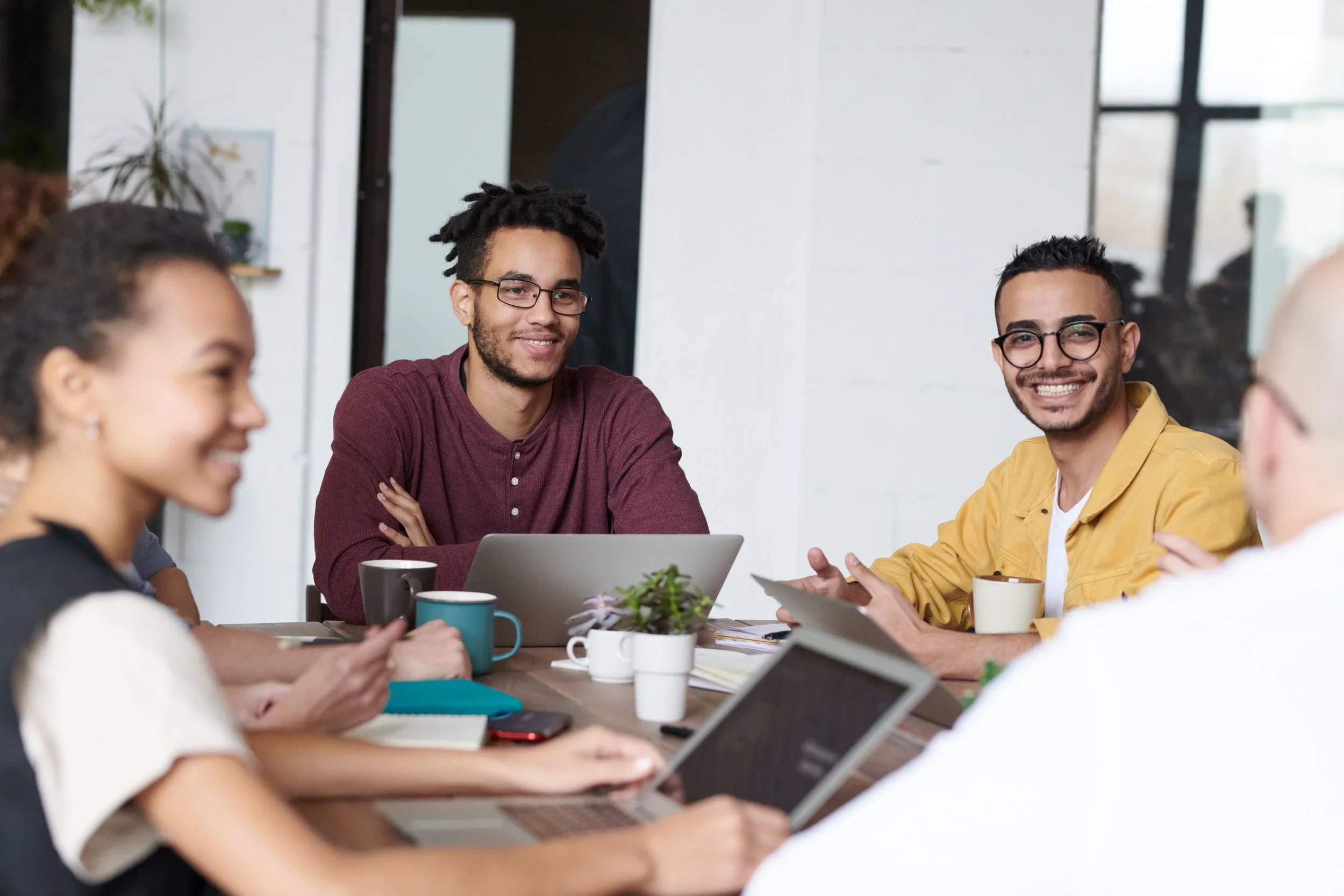 People smiling and collaborating around a table during a team meeting.