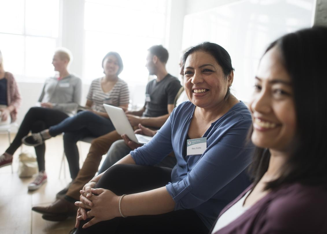 People seated together and smiling during a group workshop or discussion.