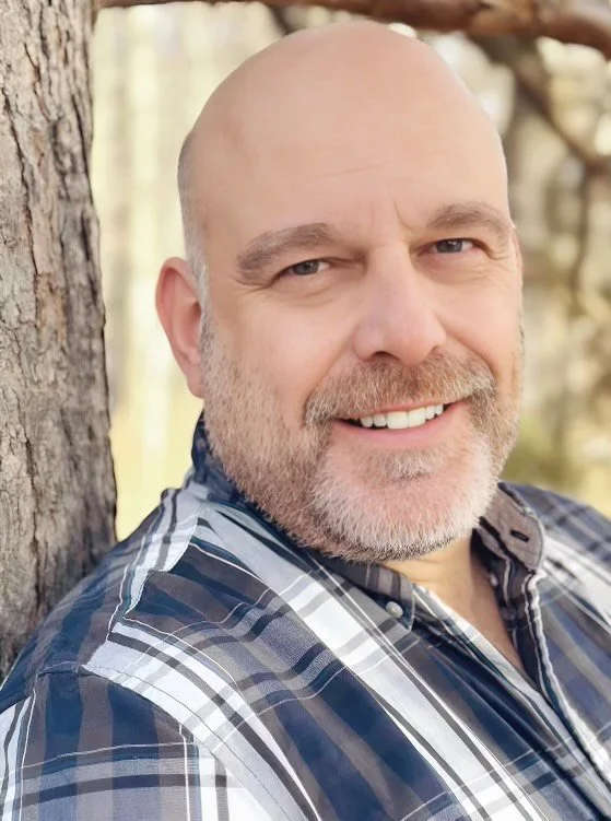 Peter Miller smiling outdoors in a forest setting