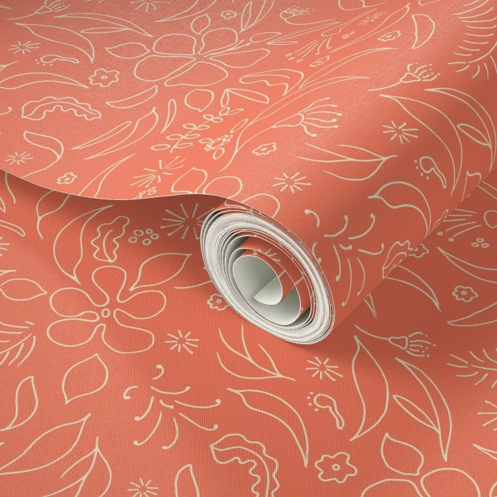 A roll of coral and cream wrapping paper with white floral and leaf patterns.