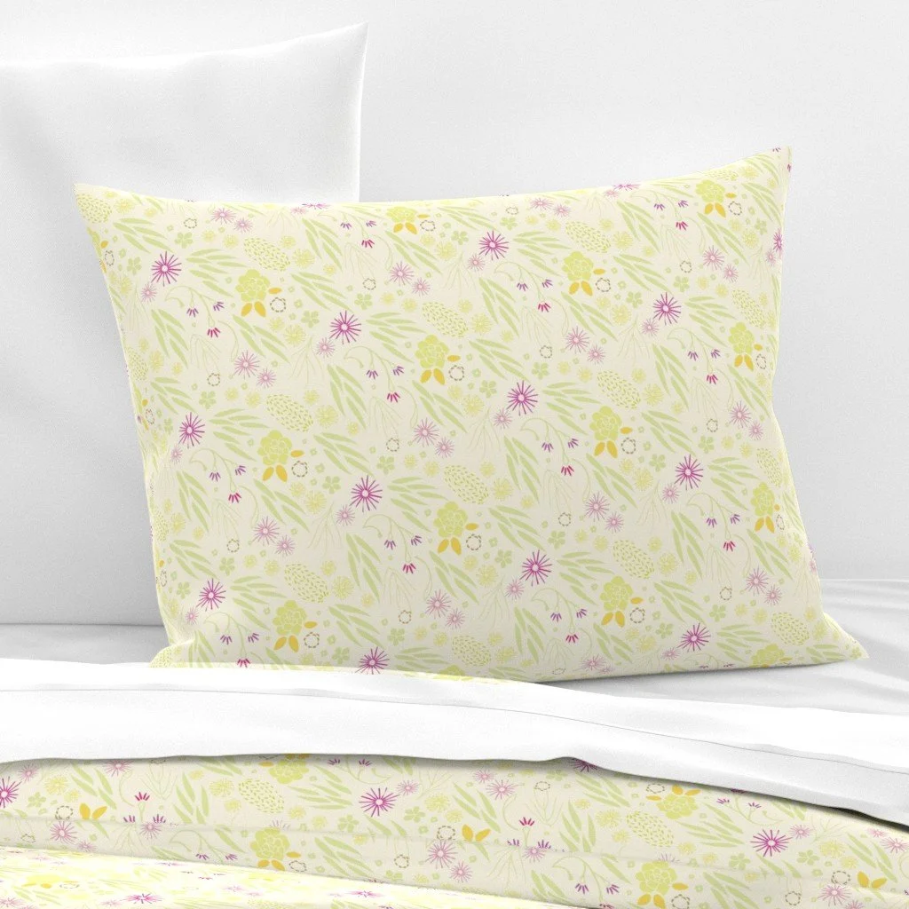Decorative pillow with a floral pattern in yellow and purple on a bed with white sheets and pillowcases.
