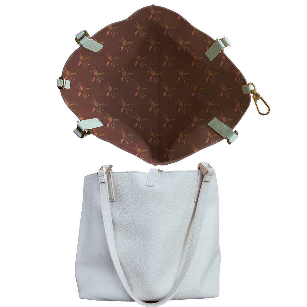 Top view of the Inner lining of a handbag with palm tree designs and a side view of a white leather tote bag with straps.