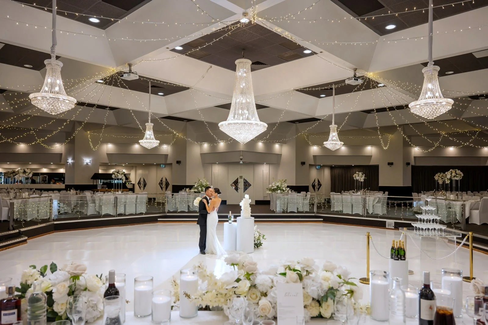 A bride and groom dancing in a decorated wedding reception hall with chandeliers and string lights at Donato the venue in Adelaide