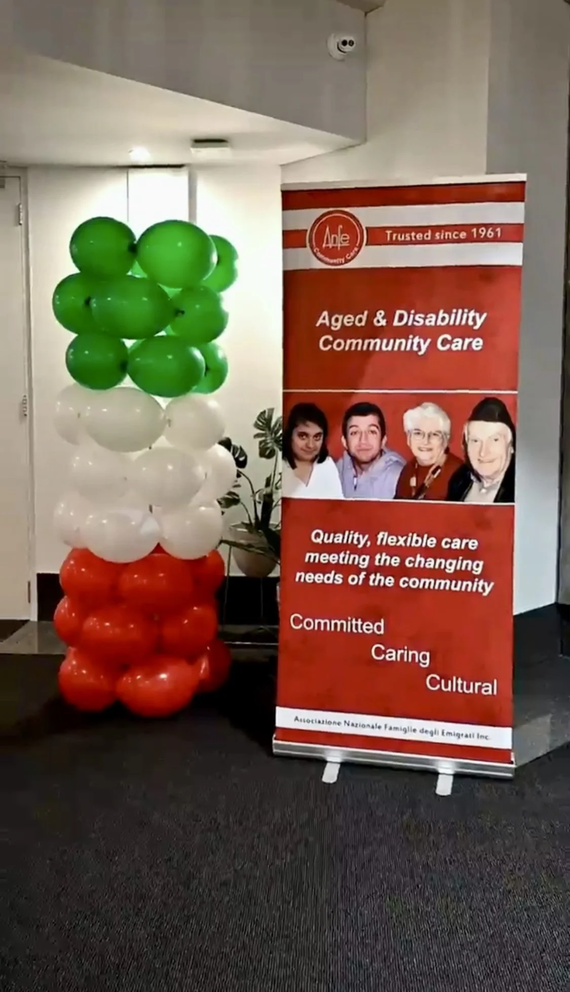 A vertical banner with red and white colors displaying information about aged and disability community care, featuring photos of four diverse individuals and text emphasizing quality, flexibility, and community needs. To the left, there is a balloon 