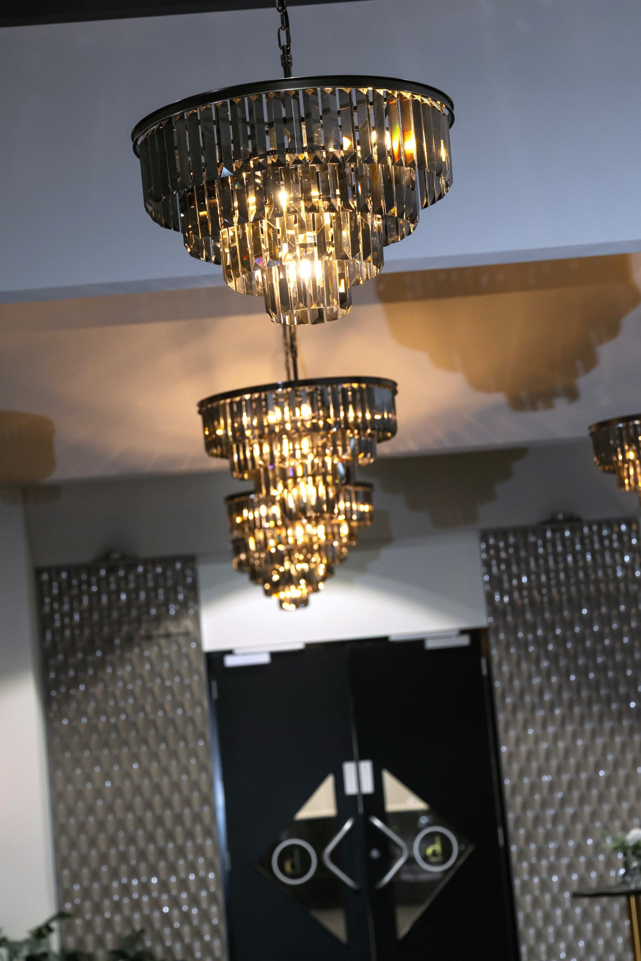 Multiple crystal chandeliers hanging from the ceiling in a modern interior space.