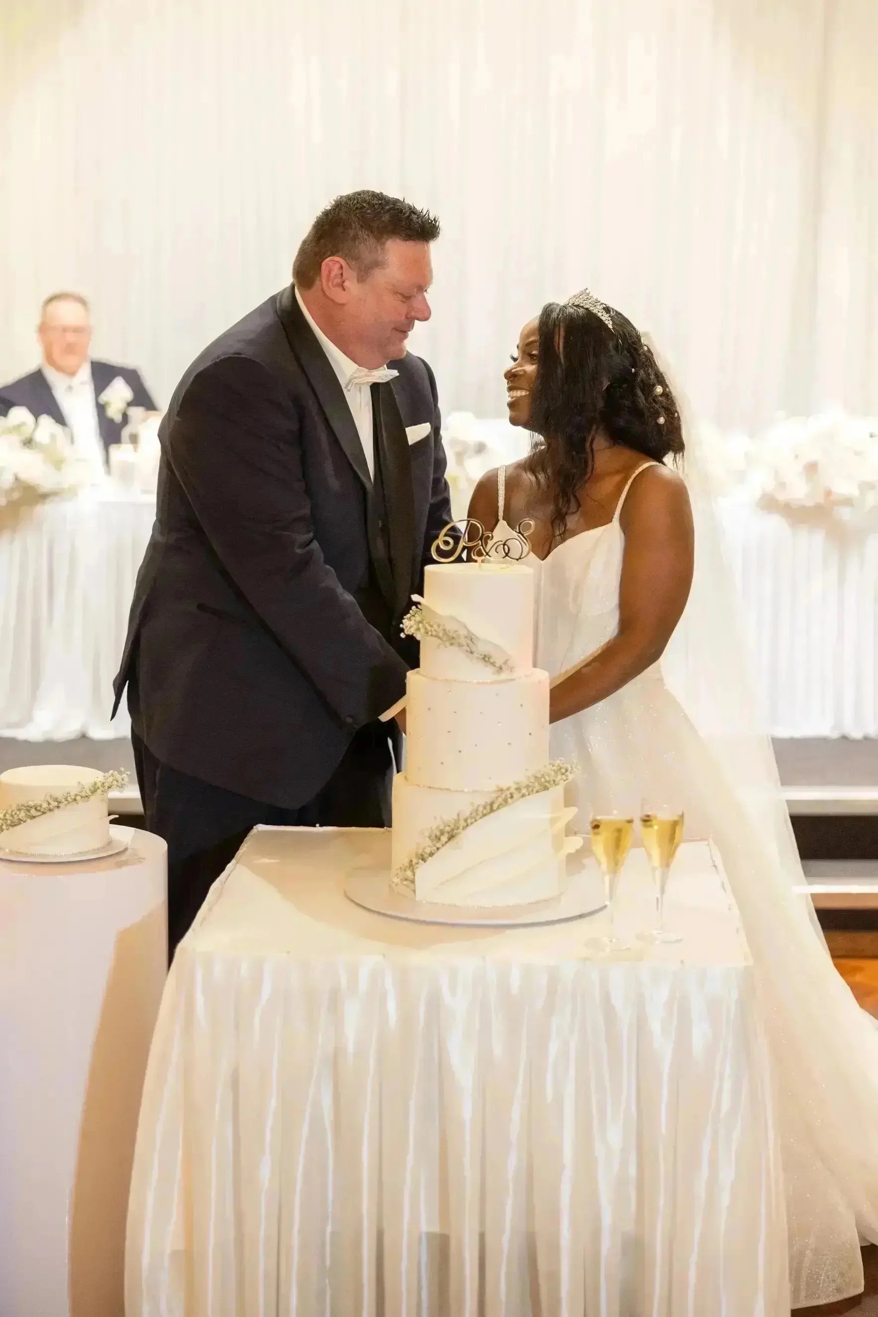 The Bride and Groom looking at each other in love infront of delicious white cake. 