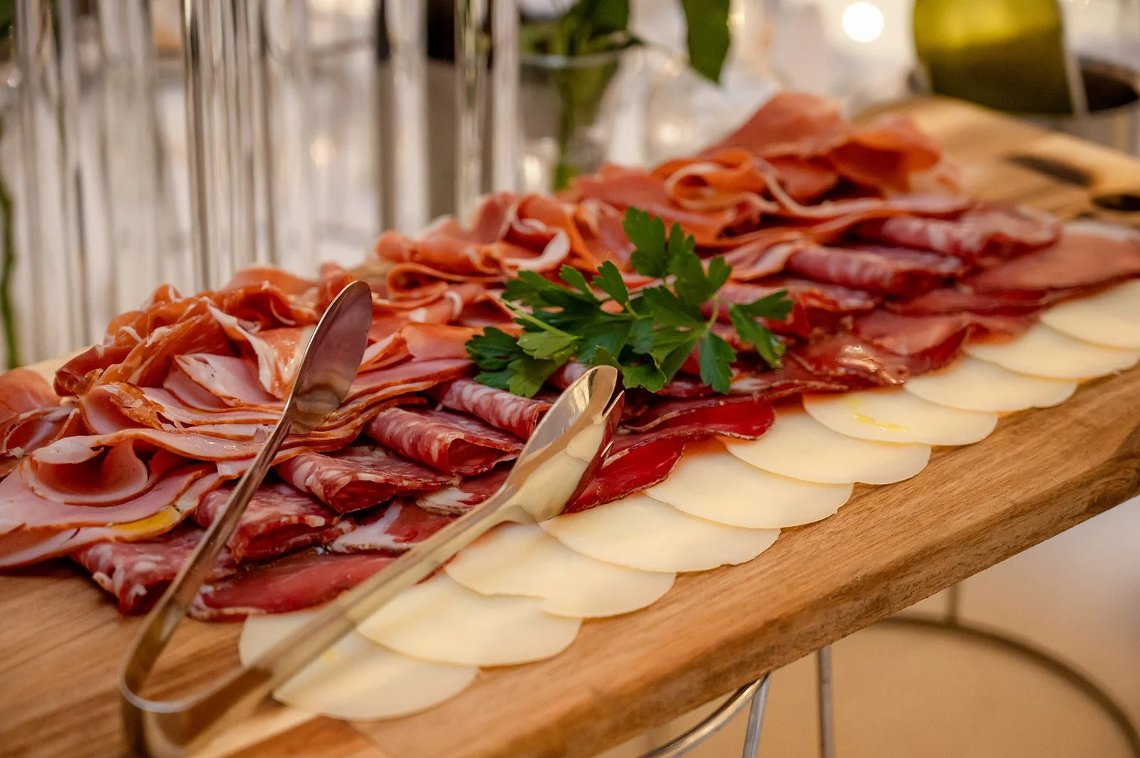 Assorted cold cuts and cheeses on a wooden platter garnished with parsley.