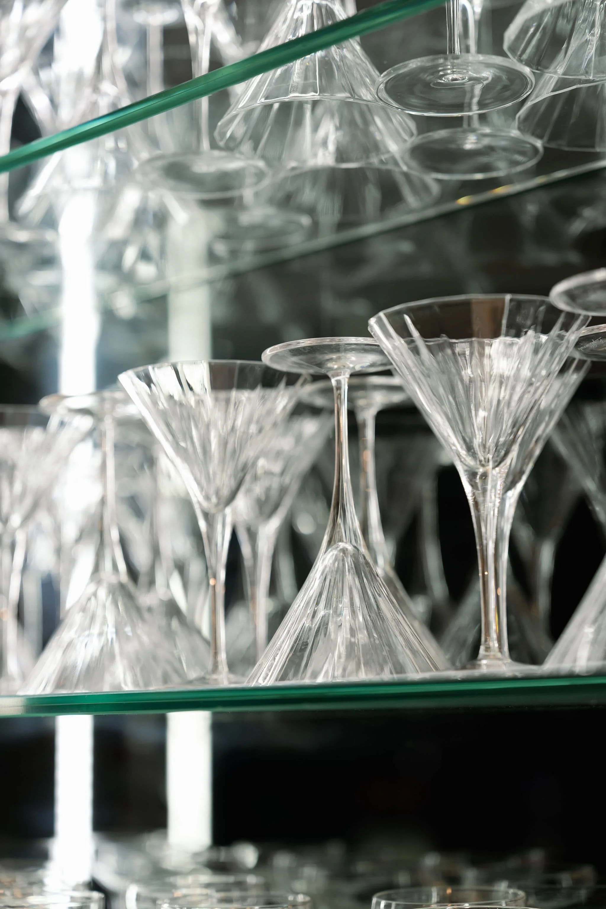 Stacked clear glass cocktail glasses displayed on shelves.