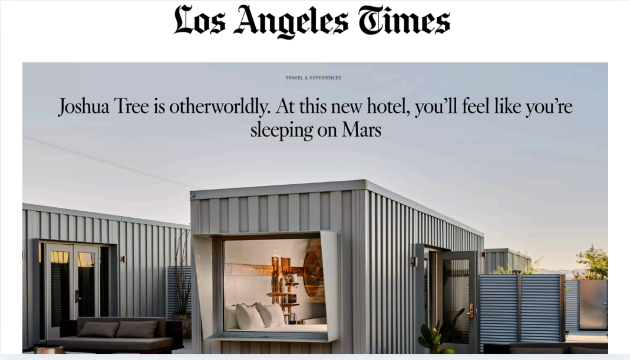 Modern rooftop patio with a cozy bed, outdoor seating, and surrounding metal building structures, with clear skies overhead.