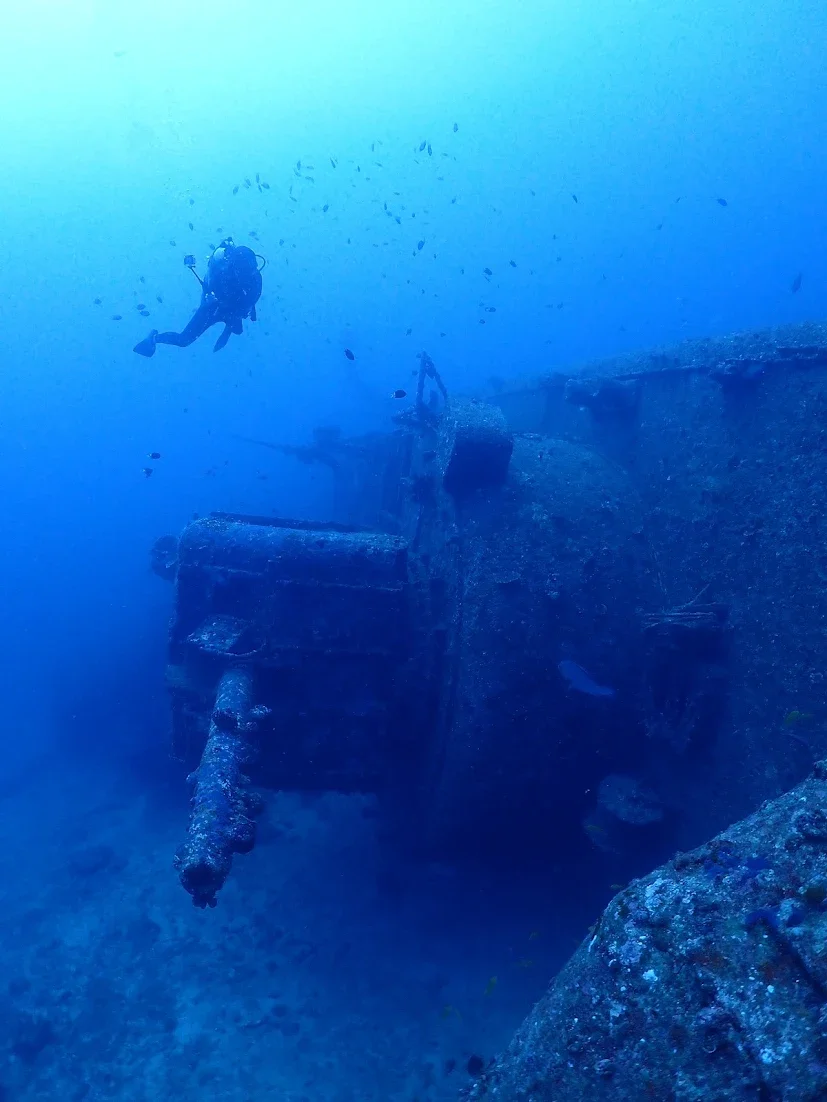 Open sea with a scuba diver near a sunken shipwreck.