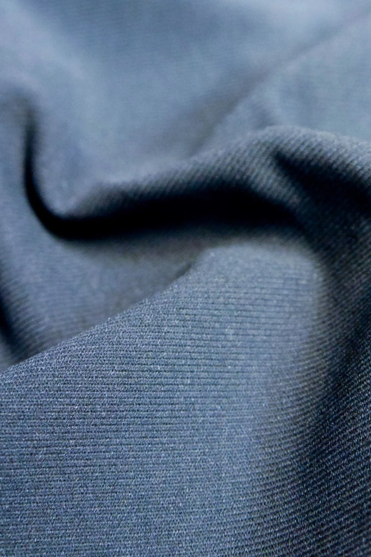 Close-up photo of gray fabric with a folded section, showing texture and stitching details.