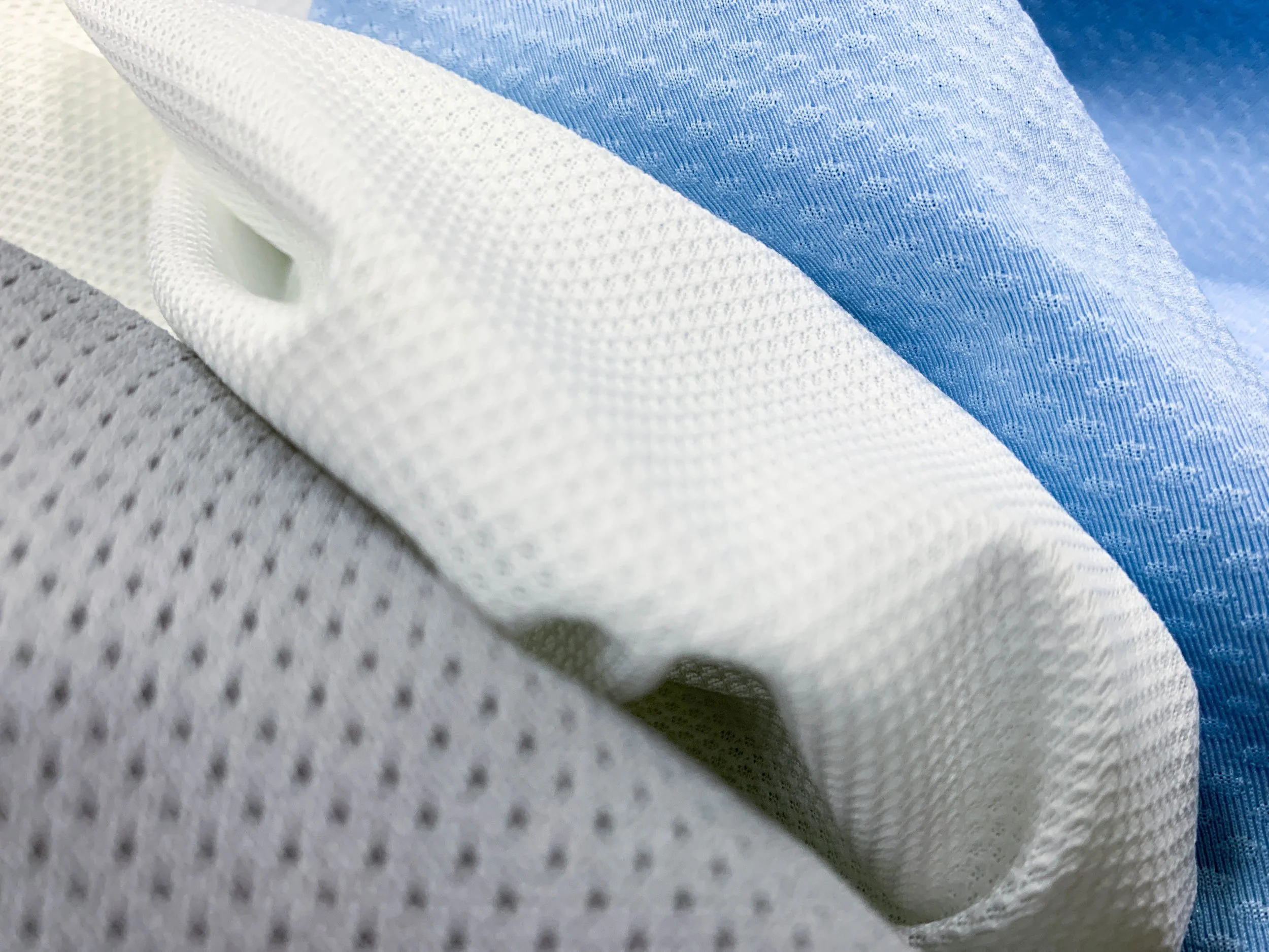Close-up of layered fabric with white, blue, and gray textures and patterns.