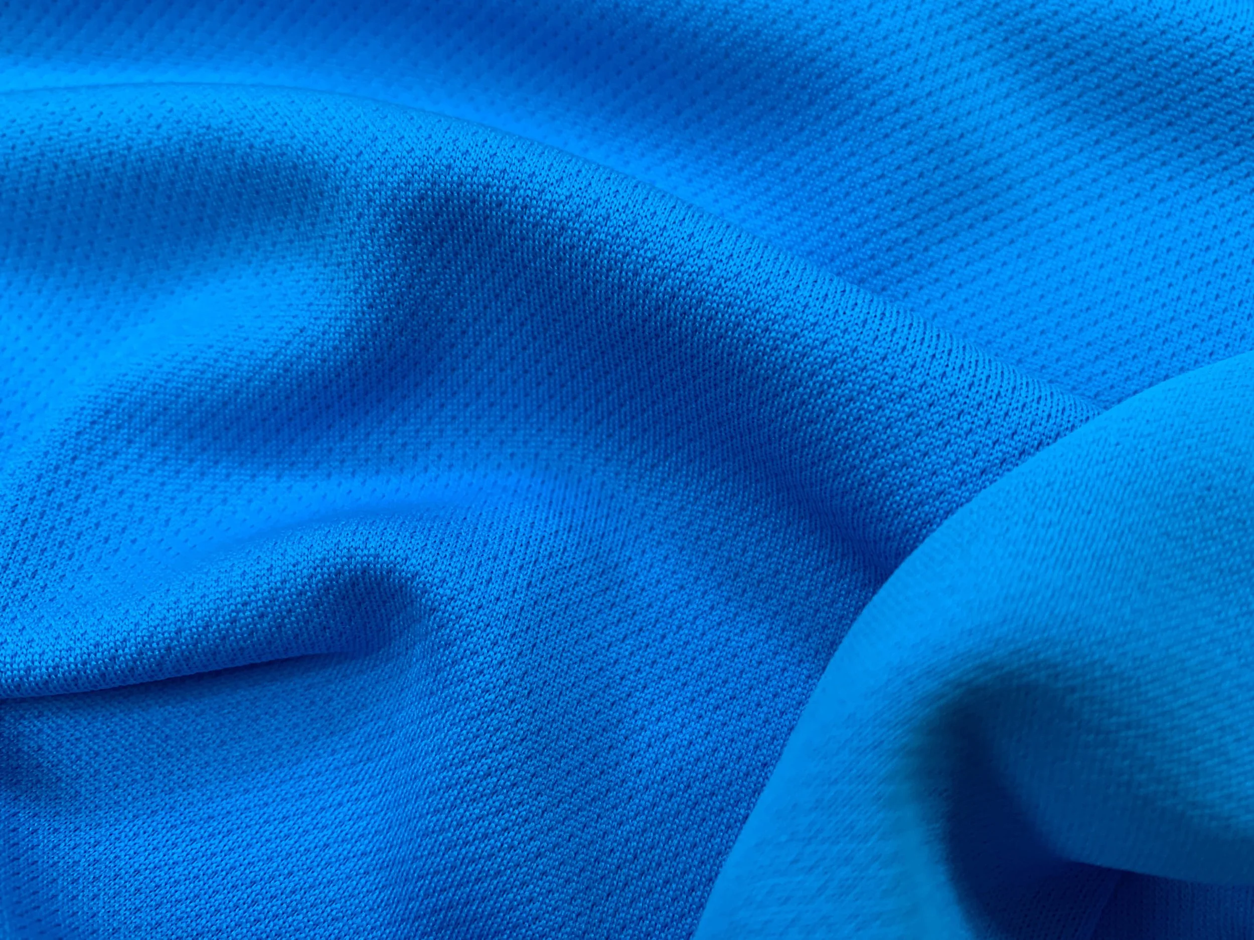 Close-up of vibrant blue textured fabric with folds and smooth surface.