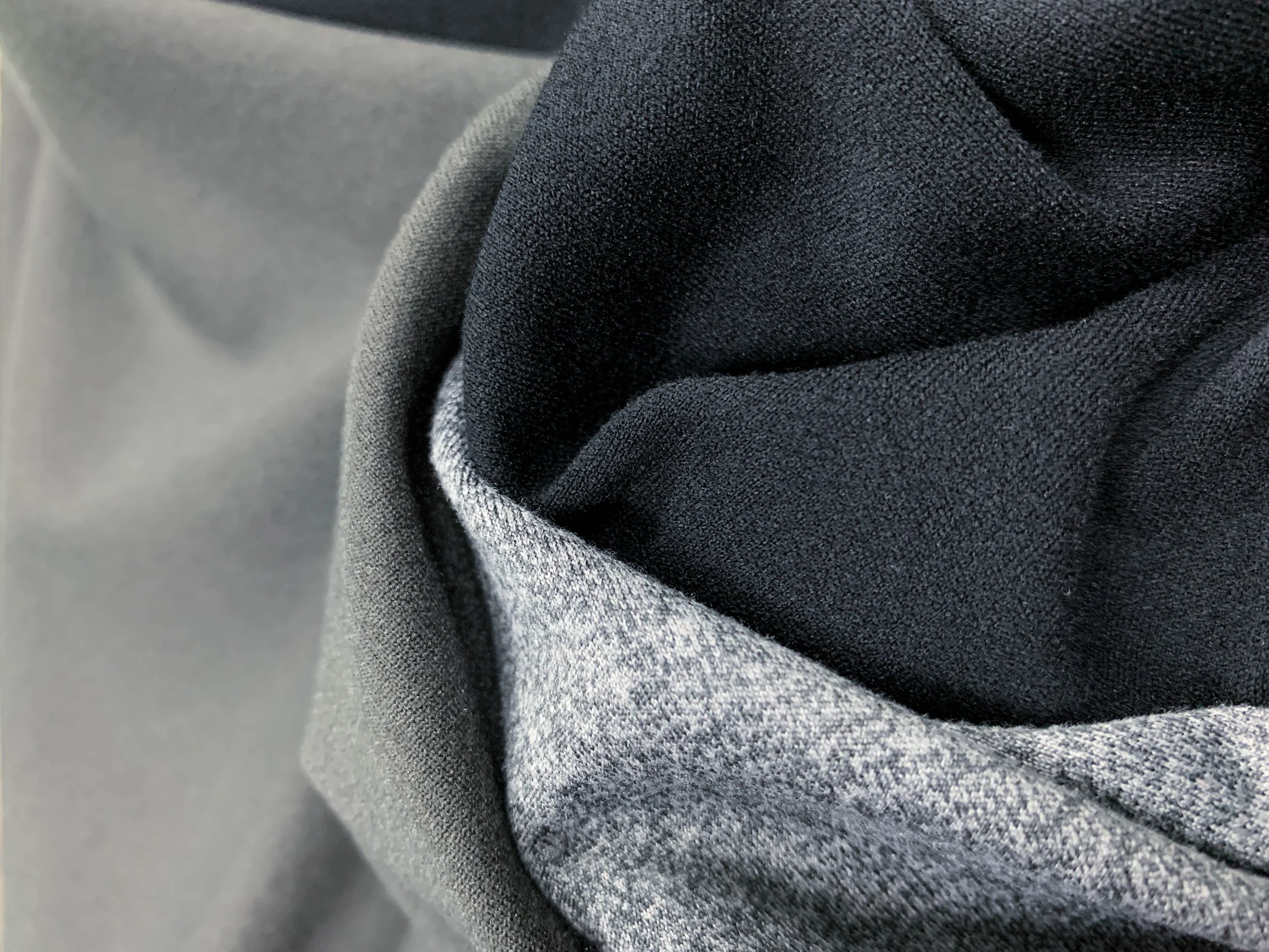 DaFon knitted functional fabrics' close-up of folded fabrics in shades of gray and black.