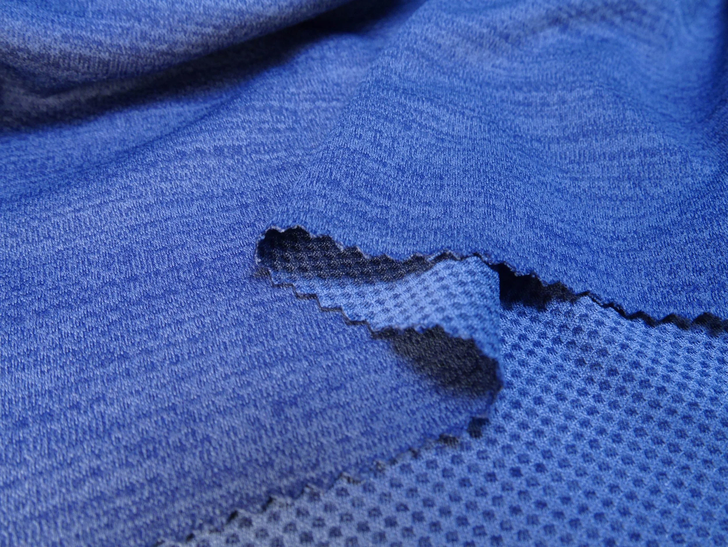 Close-up of bright blue fabric with a small tear or hole revealing darker material underneath.