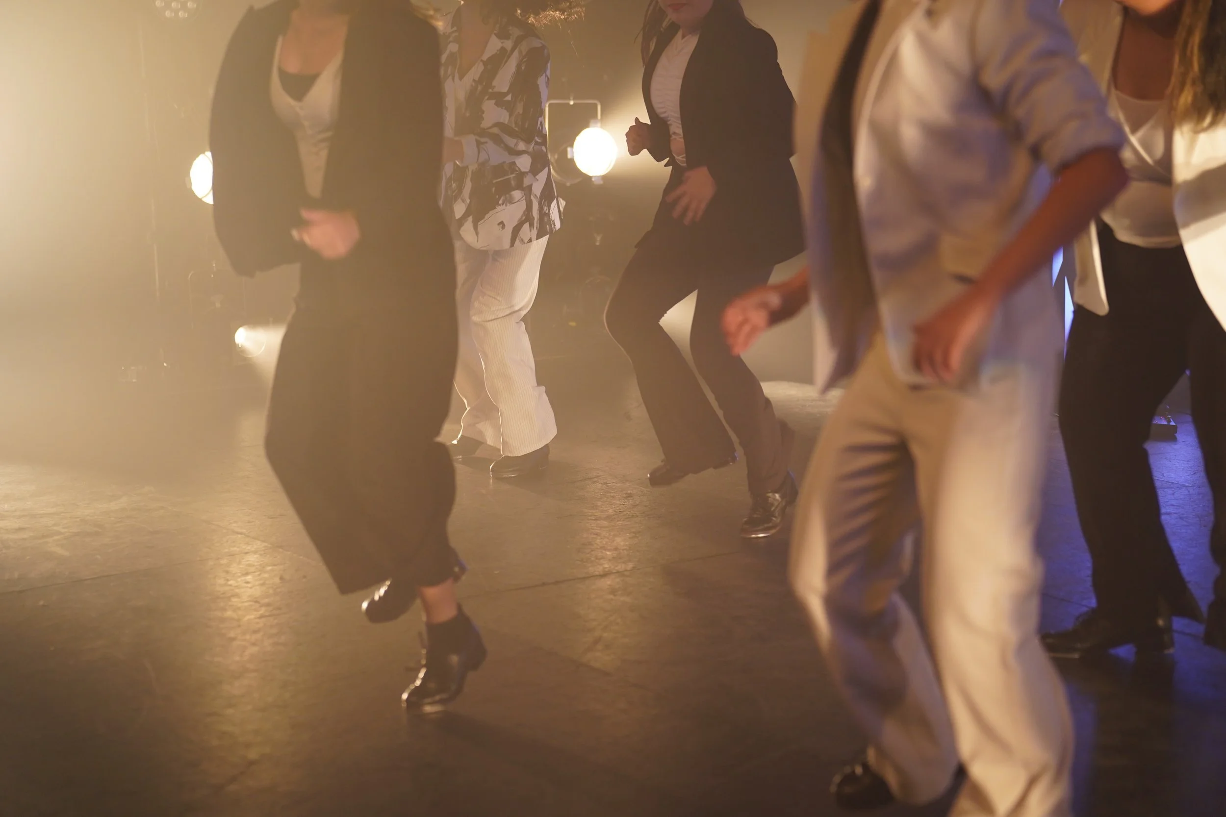 People dancing in a dimly lit room with warm lighting.