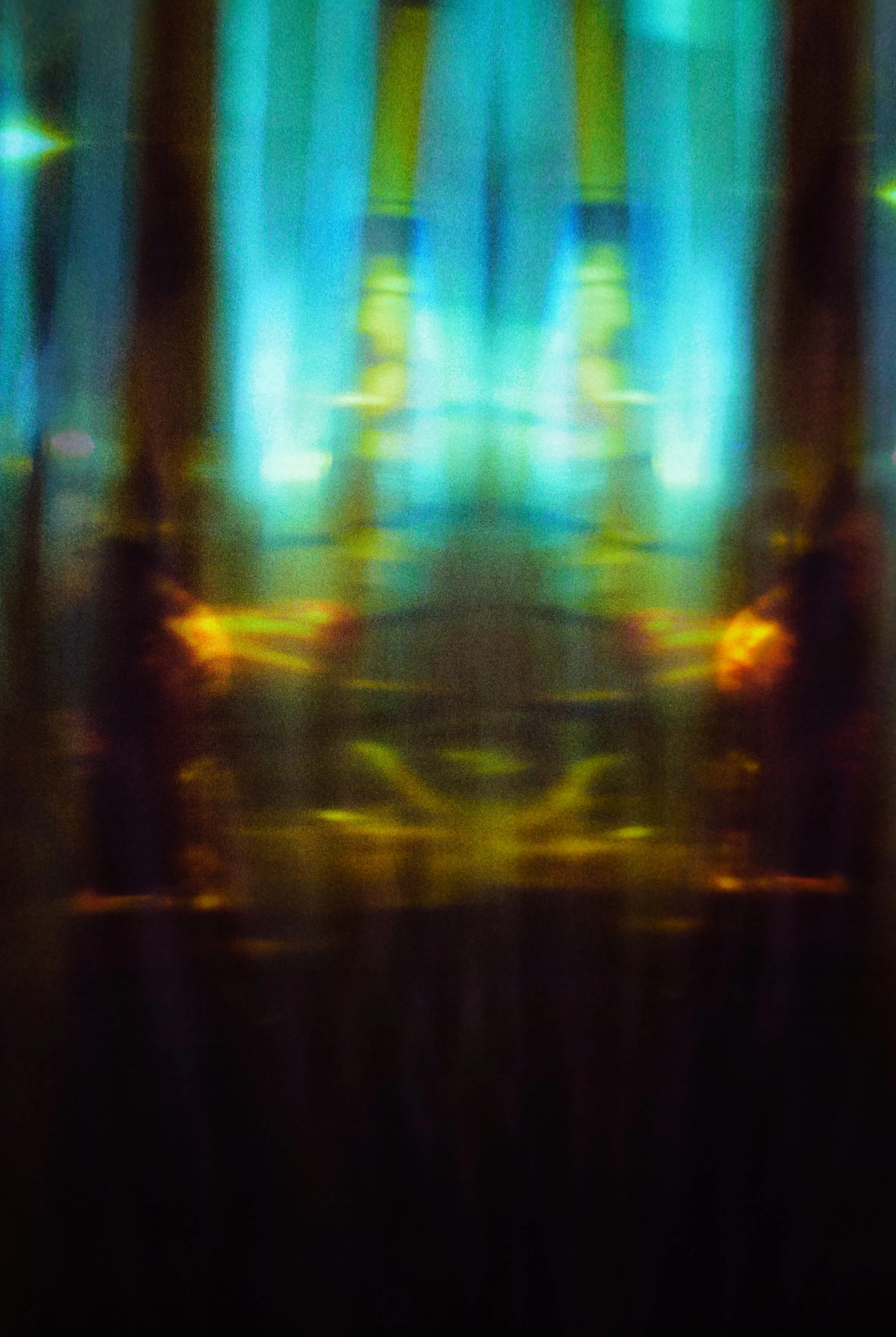 Afterlight

The heat sits inside this photograph. I remember standing in front of the izakaya, the air thick enough to feel on the skin, looking through a plastic tarp that had gone soft with humidity. Inside, the light is blue and yellow, rising in 
