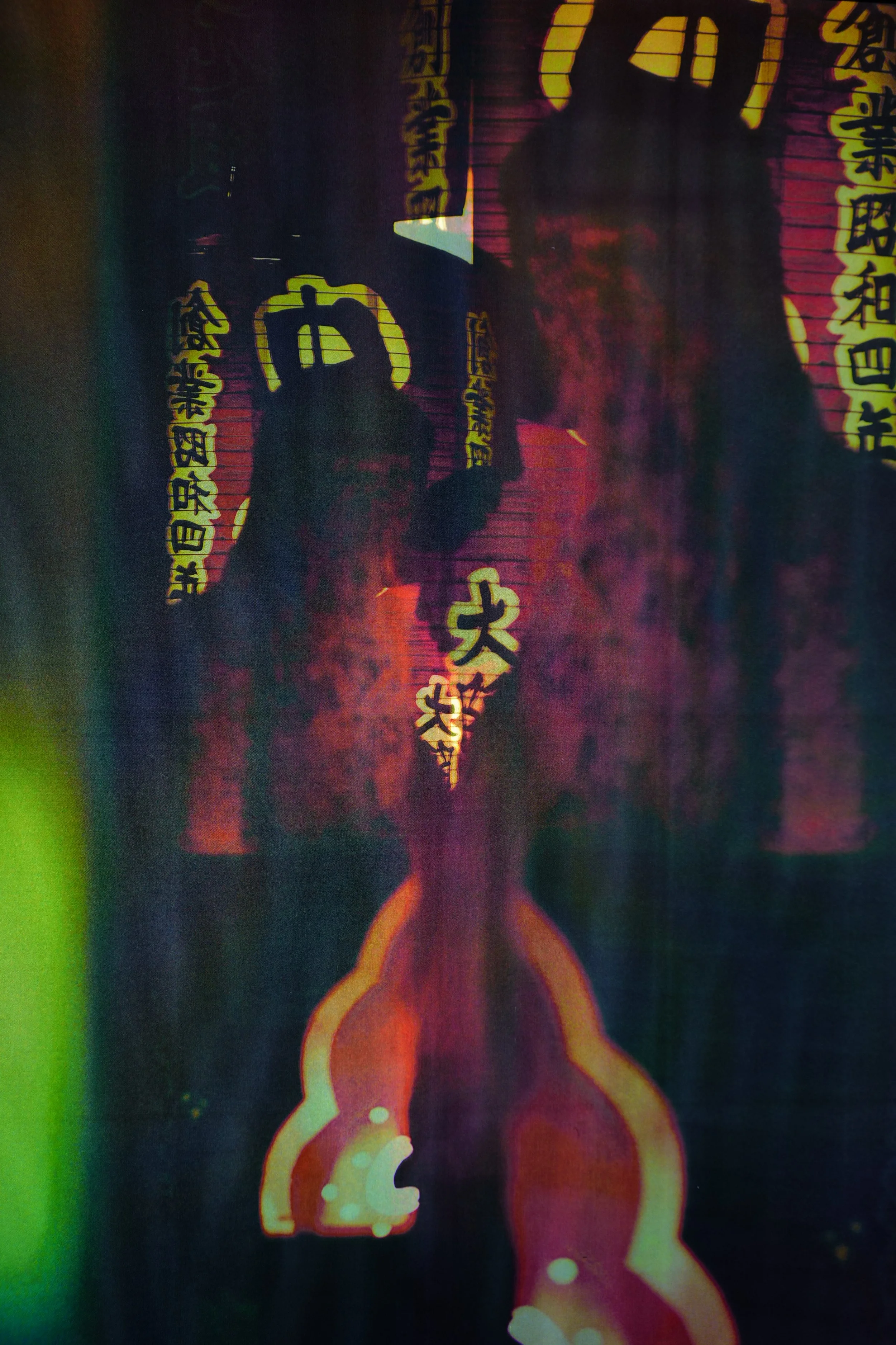 Lantern Spell

This image feels like walking past a sheet of glass that has decided to keep something of you. Lanterns and vertical bands of text glow in reds and yellows, stacked down the centre of the frame. Behind them, a darker shape rises: a fig