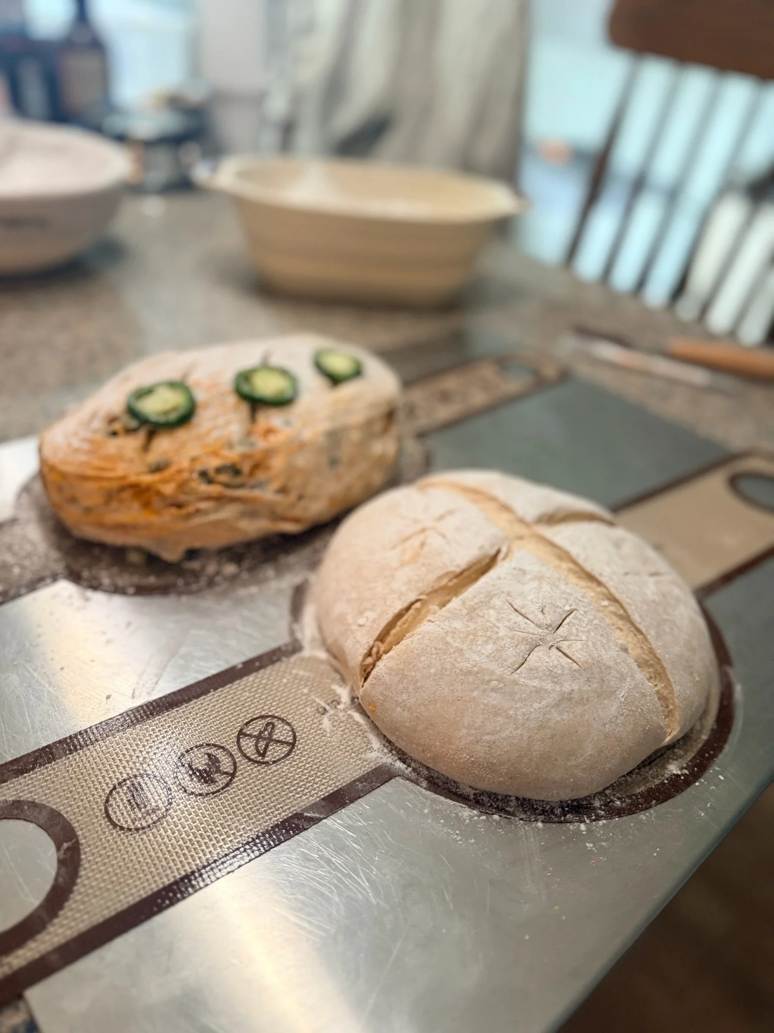 Unbaked bread rolls and a loaf on a baking sheet in a kitchen.