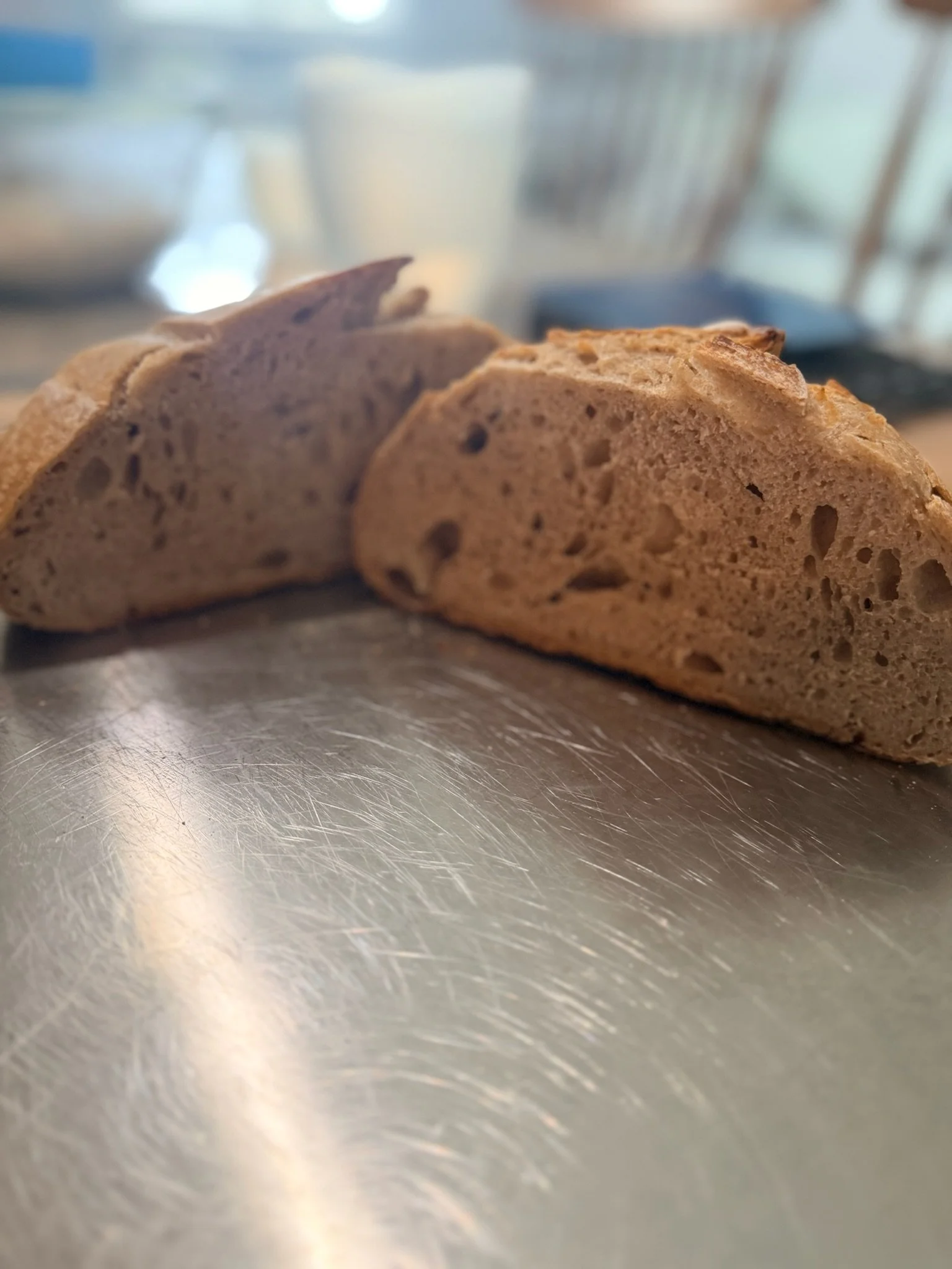 Close-up of sliced loaf bread on a shiny metallic surface in a kitchen.