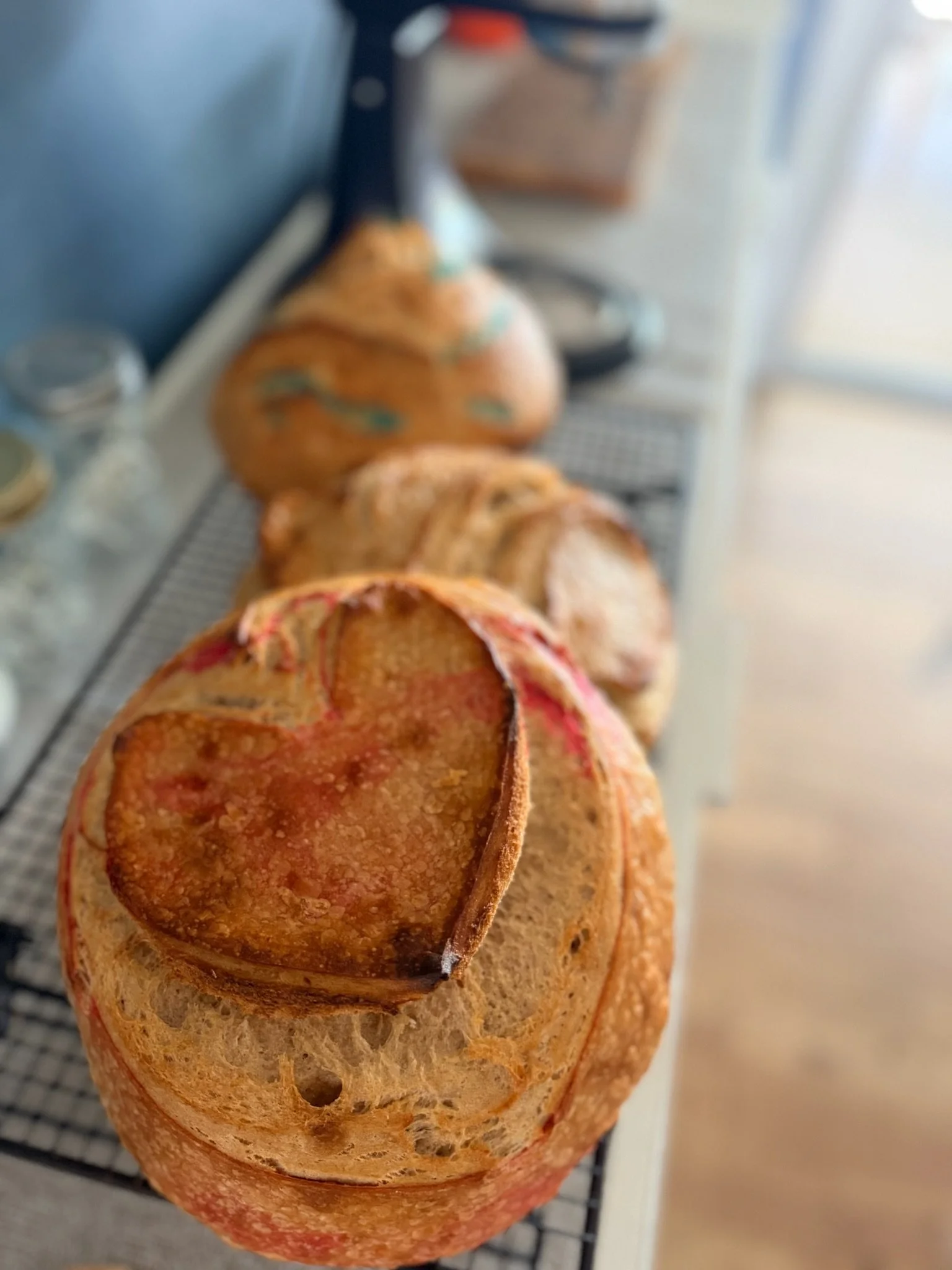 Close-up of a sliced baguette with a hollow crust and a small round hole, resting on a wire cooling rack.