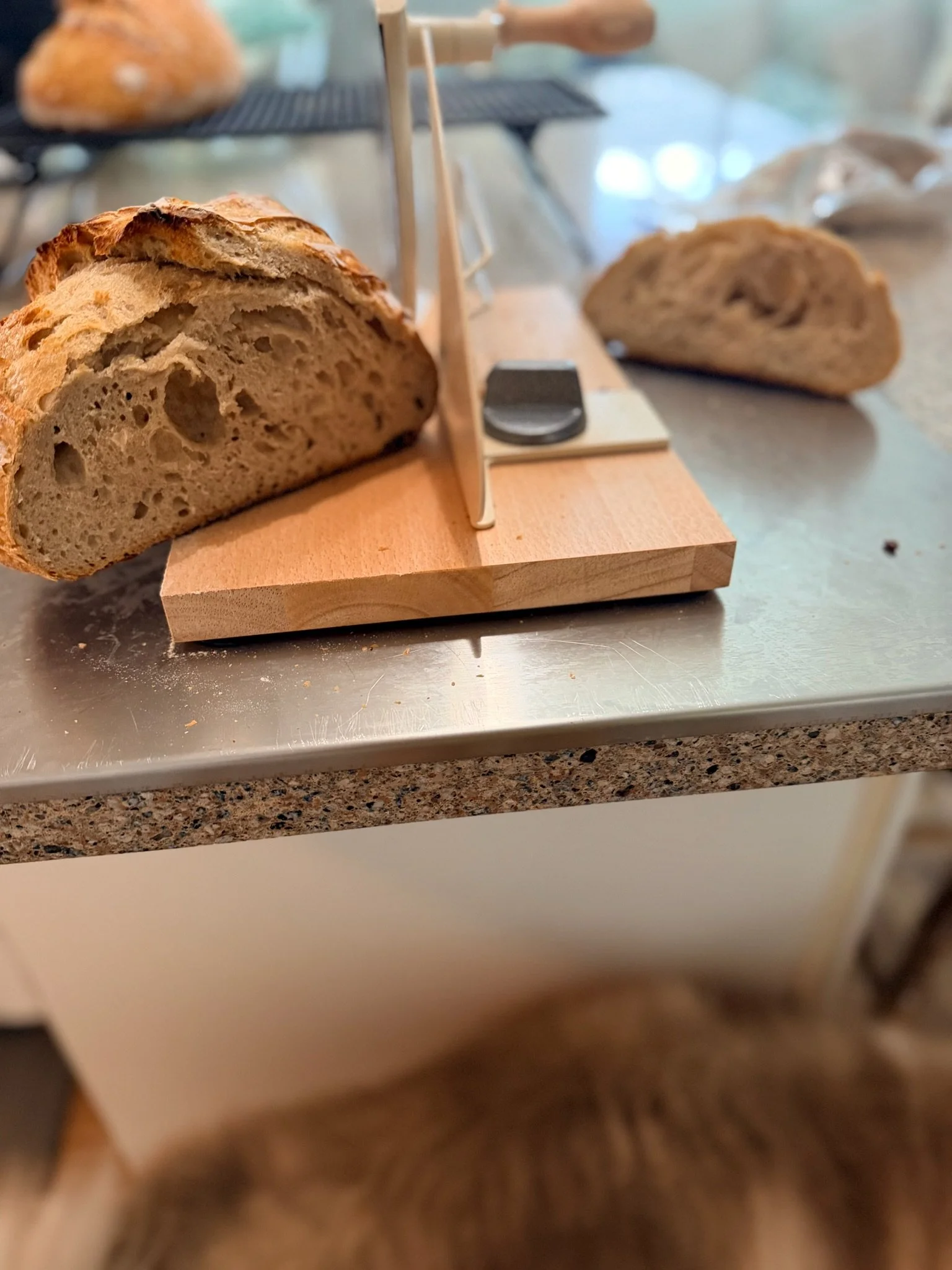 Close-up of a cut loaf of bread on a wooden cutting board, with slices of bread in the background.