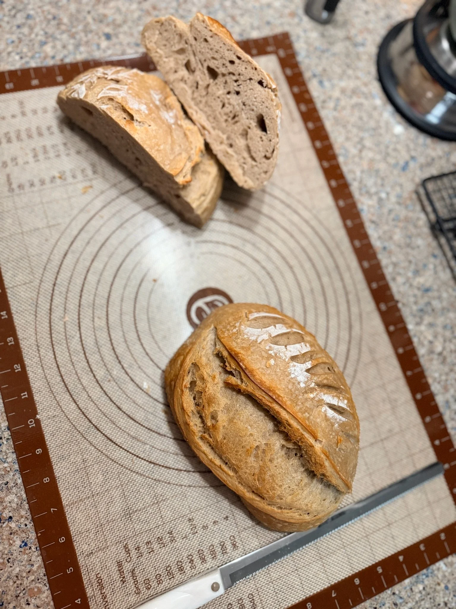 A loaf of bread cut in half on a silicone baking mat on a kitchen counter.