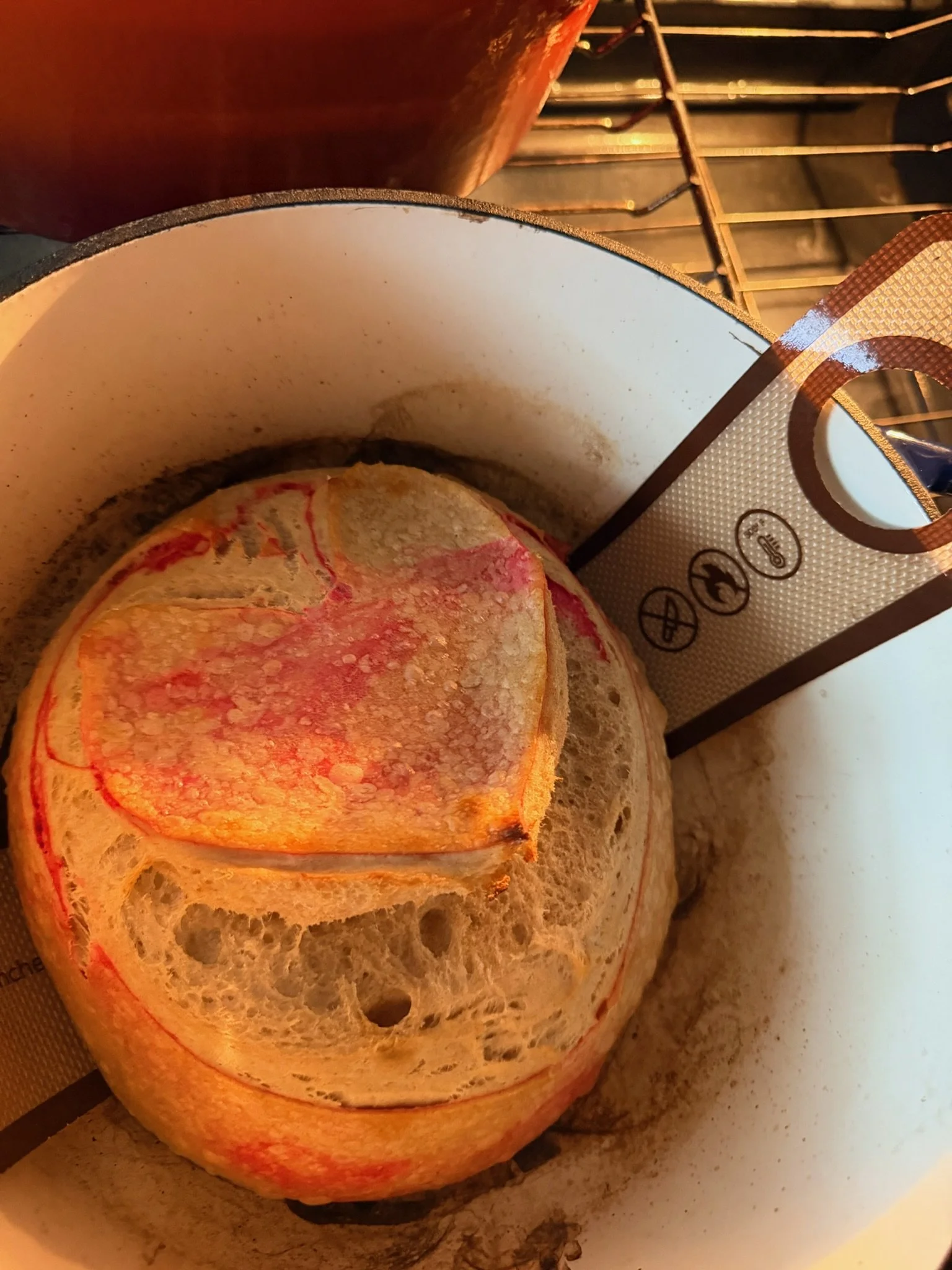 A loaf of bread on a cutting board with a slice cut from it, in a kitchen setting.