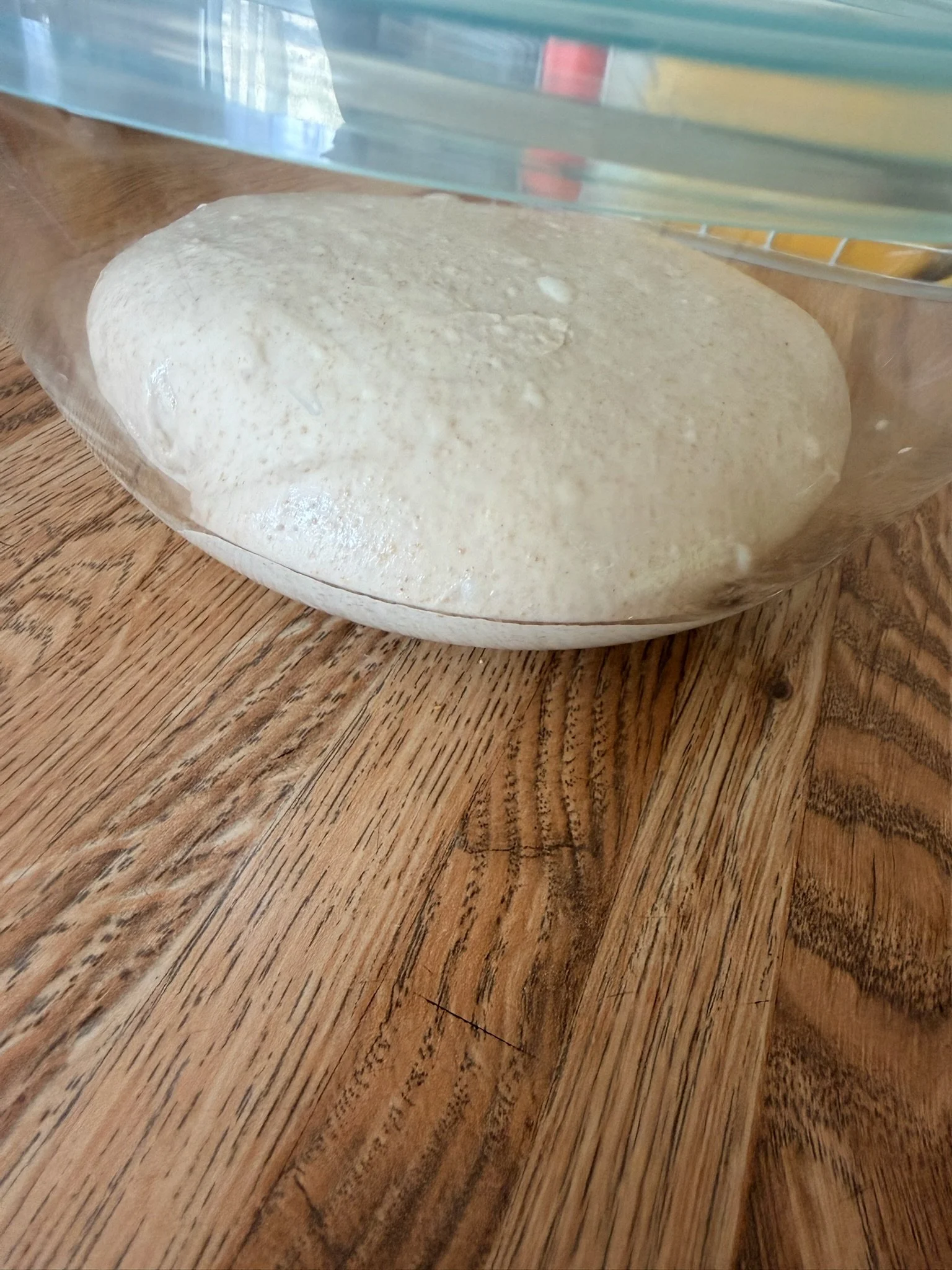 A plastic bag containing a round, white, bubbly substance resting on a wooden surface.