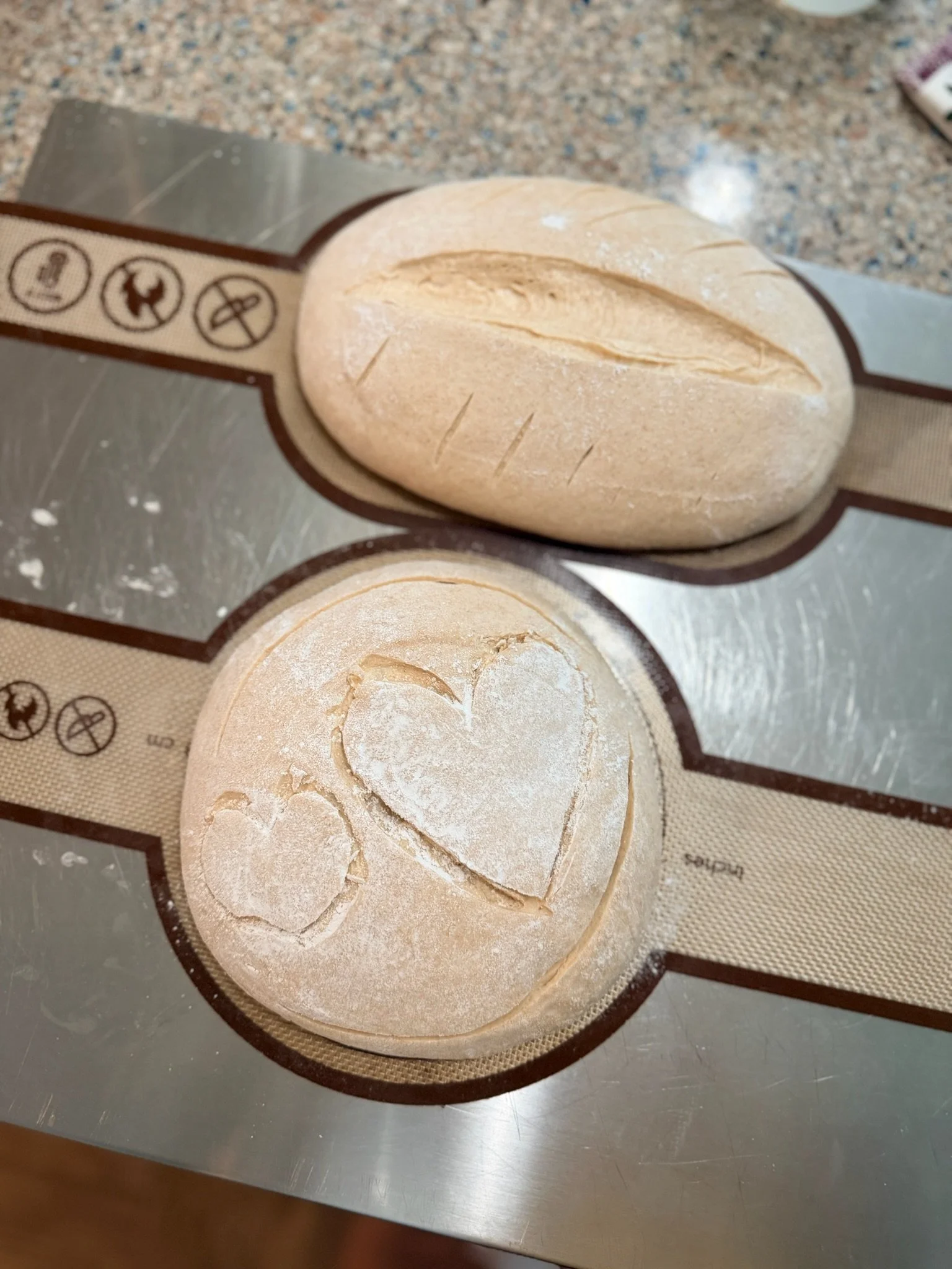 Unbaked bread rolls on a silicone baking mat on a kitchen countertop.