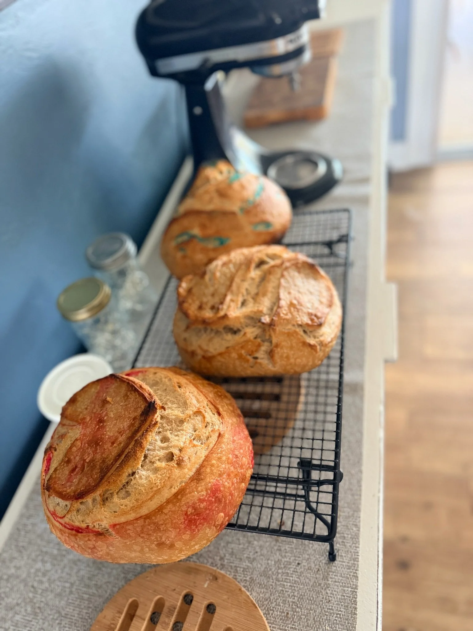 Three loaves of freshly baked bread on a wire cooling rack on a kitchen counter.