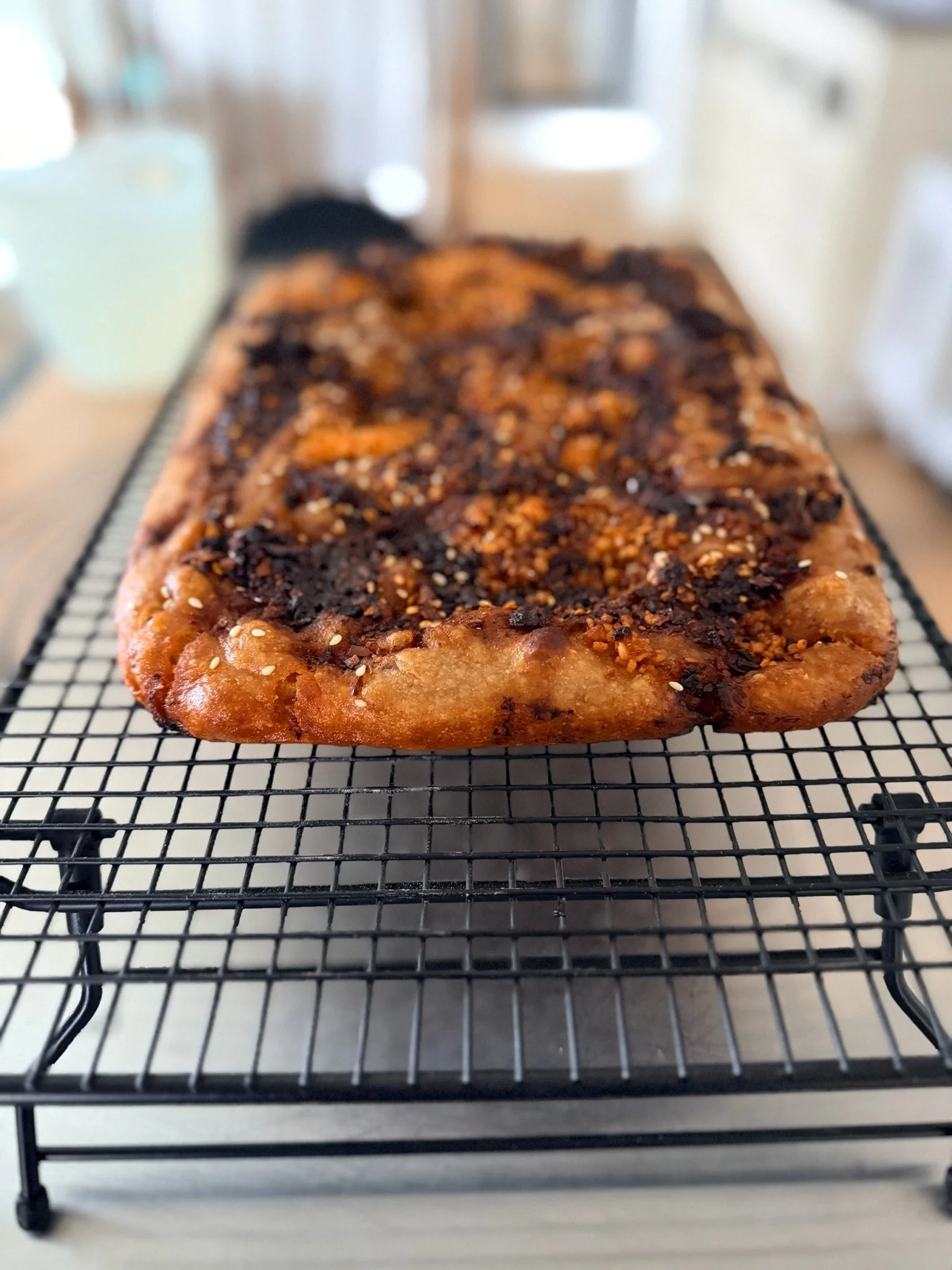 A loaf of bread with a nut topping on a wire cooling rack.